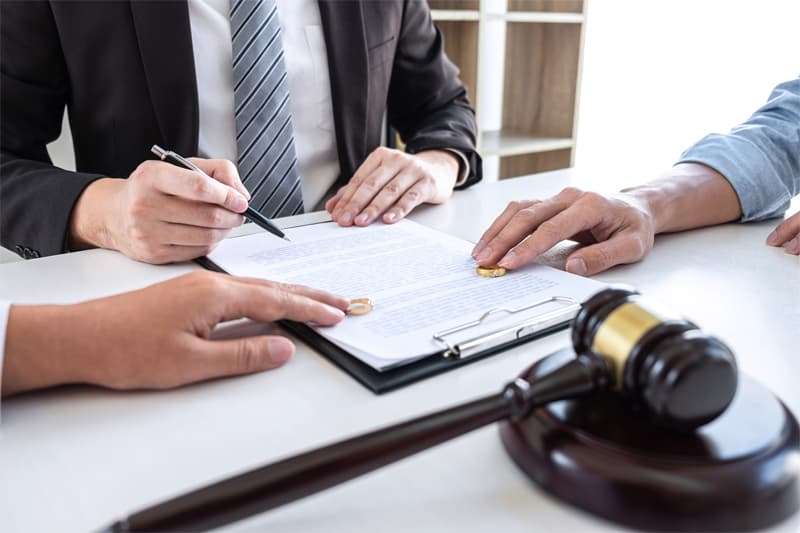 Divorce lawyer meeting with clients, clipboard with divorce papers on table